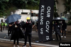 Masked protesters hold umbrellas during an anti-government rally in central Hong Kong, Oct. 6, 2019.