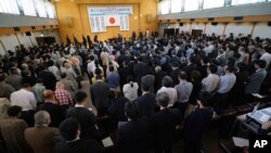 Participants bow to the Japanese flag after singing the national anthem during the annual rally on revising Japan's constitution attended by lawmakers in Tokyo, May 1, 2018. 