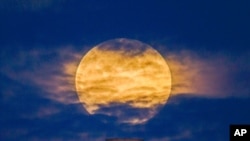 FILE - A pink supermoon rises in the night sky over Coit Tower in San Francisco, California, April 26, 2021.