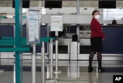 A Cathay Pacific ground support member stands next to check in counters at the Hong Kong International Airport in Hong Kong Wednesday, Oct. 21, 2020. Hong Kong airline Cathay Pacific Airways on Wednesday said it would cut 8,500 jobs and shut down…