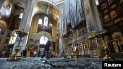 Seorang perempuan membersihkan puing-puing di dalam katedral yang rusak akibat serangan rudal Rusia di Zaporizhzhia, Ukraina 18 Oktober 2023. (REUTERS/Stringer)