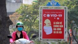 A motorcyclist drives past a poster calling people to take care of their health against the new coronavirus in Hanoi, Vietnam Tuesday, April 14, 2020. The new coronavirus causes mild or moderate symptoms for most people, but for some, especially…