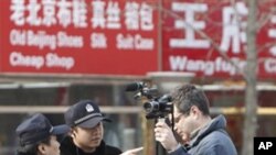 Chinese policemen ask an Associated Press cameraman to leave the area near the shopping area on Wangfujing Street in Beijing, Feb. 27, 2011.