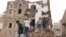 Des gens se tiennent sur les débris d'une maison qui s'est récemment effondrée en raison de fortes pluies dans le vieux quartier de Sanaa, au Yémen, le 3 mai 2020.