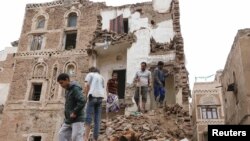 People stand on the debris of a house that recently collapsed due to heavy rains in the old quarter of Sanaa, Yemen May 3, 2020.