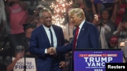 Capres Partai Republik, Donald Trump berjabat tangan dengan mantan kandidat presiden independen Robert F. Kennedy Jr. (kiri), selama rapat umum di Glendale, Arizona, AS, 23 Agustus 2024.