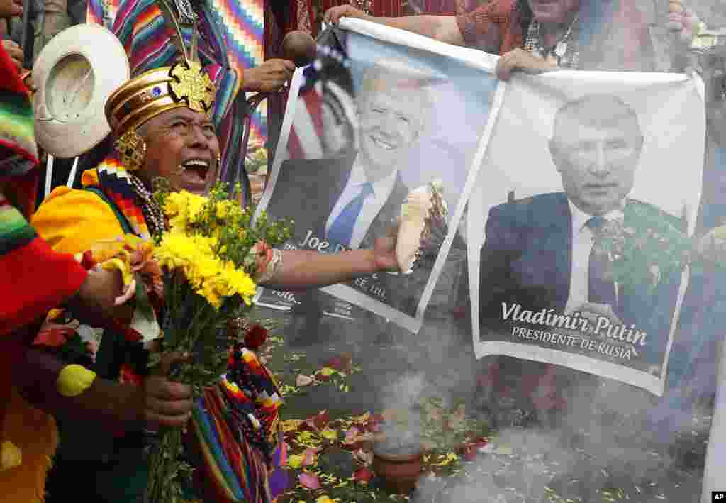 Para dukun memegang foto Presiden AS Joe Biden dan Presiden Rusia Vladimir Putin dalam ritual akhir tahun di di Lima, Peru, di mana para dukun tersebut memberikan prediksi mereka tentang kondisi politik dan sosial pada tahun mendantang.