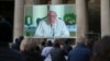 People look at a giant screen in St.Peter's Square, at the Vatican, showing Pope Francis reciting the Angelus noon prayer from his residence, after he decided not to appear at the window of his studio because of a persistent cold, Dec. 22, 2024.