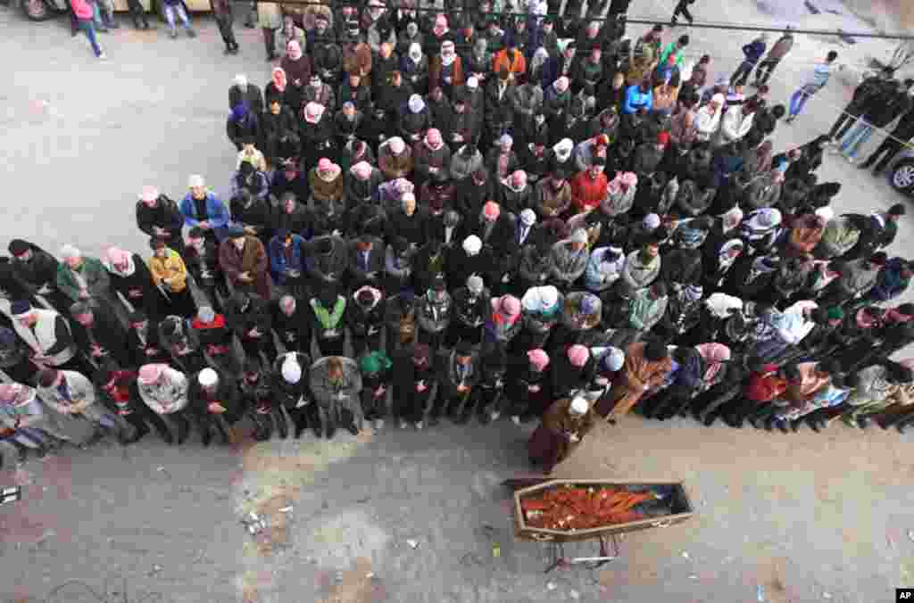 People pray by the coffin of a member of the Free Syrian Army who was killed by civilians loyal to President Bashar Al Assad, near Idlib, February 29, 2012. (Reuters)