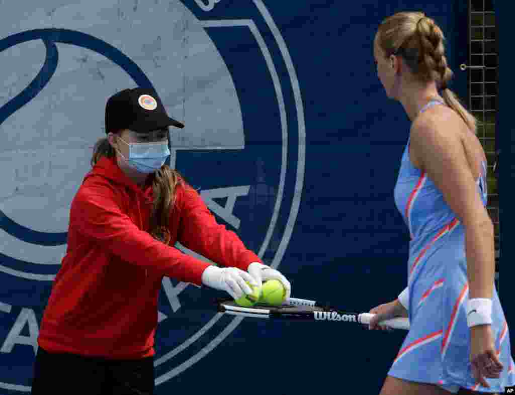 A ball girl wearing a face mask to protect against coronavirus hands over balls to Petra Kvitova during her Czech Tennis President's Cup charity tournament match against Barbora Krejcikova in Prague, Czech Republic. 