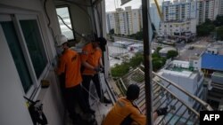 Petugas pemadam kebakaran memperbaiki pelindung dan pendingin ruangan yang rusak akibat terjangan angin kencang Topan Maysak, di apartemen dekat Pantai Gwangalli di Busan, 3 September 2020. 