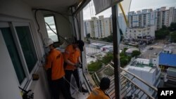 Fire department members secure a railing and air conditioning unit that were left hanging from a shattered window during high winds from Typhoon Maysak at an apartment near Gwangalli beach in Busan on September 3, 2020. - At least one person was…