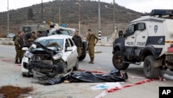 Israeli soldiers and border police officers stand near the body of a Palestinian, center, who rammed his vehicle into a group of Israelis standing at a hitchhiking station, in the West Bank, near the Palestinian town of Nablus, Nov. 8, 2015.