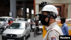 지난 11일 인도 뉴델리에서 열화상카메라를 착용한 경찰이 출근길 시민들의 체온을 확인하고 있다.