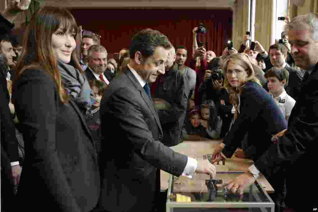 El presidente saliente Nicolas Sarkozy y la primera dama, Carla Bruni-Sarkozy, en el momento en que el mandatario vot&oacute; en Par&iacute;s. (AP)