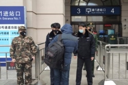 Security officers check a person at an entrance to the Hankou Railway Station in Wuhan in central China's Hubei Province, Jan. 23, 2020. China closed off a city of more than 11 million people Thursday in an effort to try to contain a deadly illness.