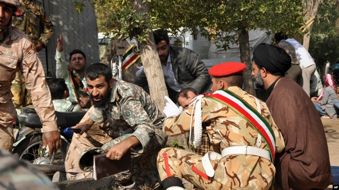 In this photo provided by the Iranian Students' News Agency, ISNA, Iranian armed forces members and civilians take cover in a shooting attack during a military parade marking the 38th anniversary of Iraq's 1980 invasion of Iran, in the southwestern city of Ahvaz, Iran, Sept. 22, 2018.