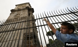 A man points at the damaged part of the ARch of Constantine after lightning struck it during a storm in Rome, Sept. 3, 2024.