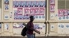 A man offering nail polish services walks in front of electoral posters outside the Municipal Market in Maputo, Mozambique, on Oct. 04, 2024. Voters head to the polls on Oct. 9, 2024 to elect their next president. 