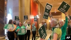 FILE - Supporters of a proposed Minnesota Equal Rights Amendment, known as the ERA, held signs support outside the Minnesota House in the State Capitol building in St. Paul, Minnesota, May 17, 2024. 