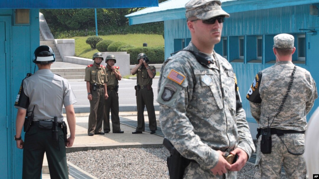 In this July 27, 2014, file photo, North Korean army soldiers watch the south side while South Korean, left, and U.S. Army soldiers stand guard at the truce villages of Panmunjom in Paju, South Korea. 