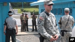 In this July 27, 2014, file photo, North Korean army soldiers watch the south side while South Korean, left, and U.S. Army soldiers stand guard at the truce villages of Panmunjom in Paju, South Korea. 