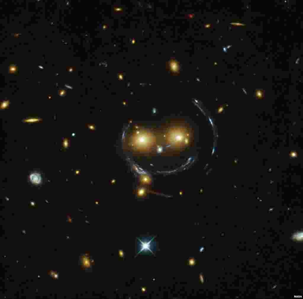 In the center of this image, taken with the NASA/ESA Hubble Space Telescope, is the galaxy cluster SDSS J1038+4849 and it seems to be smiling.