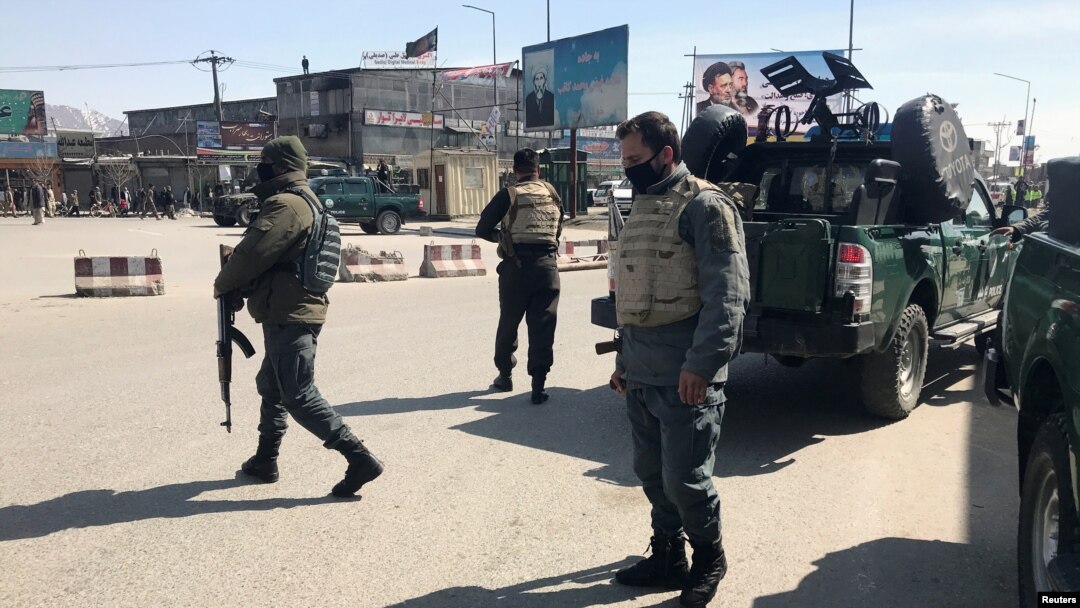 FILE - Policemen keep watch near the side of an attack in Kabul, Afghanistan, March 7, 2019.