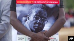 Un partisan du président zimbabwéen Robert Mugabe tient le portrait de celui-ci lors des célébrations du 93e anniversaire de celui-ci à Matopos, dans la banlieue de Bulawayo, 25 février 2017. 