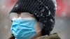 Una mujer en Beijing, usa una mascarilla al caminar por una calle de la ciudad durante una nevada, el domingo 2 de febrero de 2020. China informó que las muertes por el coronavirus de Wuhan subieron a 304.