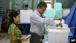 A couple cast their vote at a polling booth for advance voting in central in Yangon, Myanmar, Nov. 6, 2015.