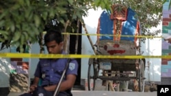 A Bangladeshi policeman sits next to a cycle rickshaw, on which Japanese citizen Kunio Hoshi was reported to be traveling while he was killed at Mahiganj village in Rangpur district, 300 kilometers (185 miles) north of Dhaka, Bangladesh, Oct. 4, 2015. 