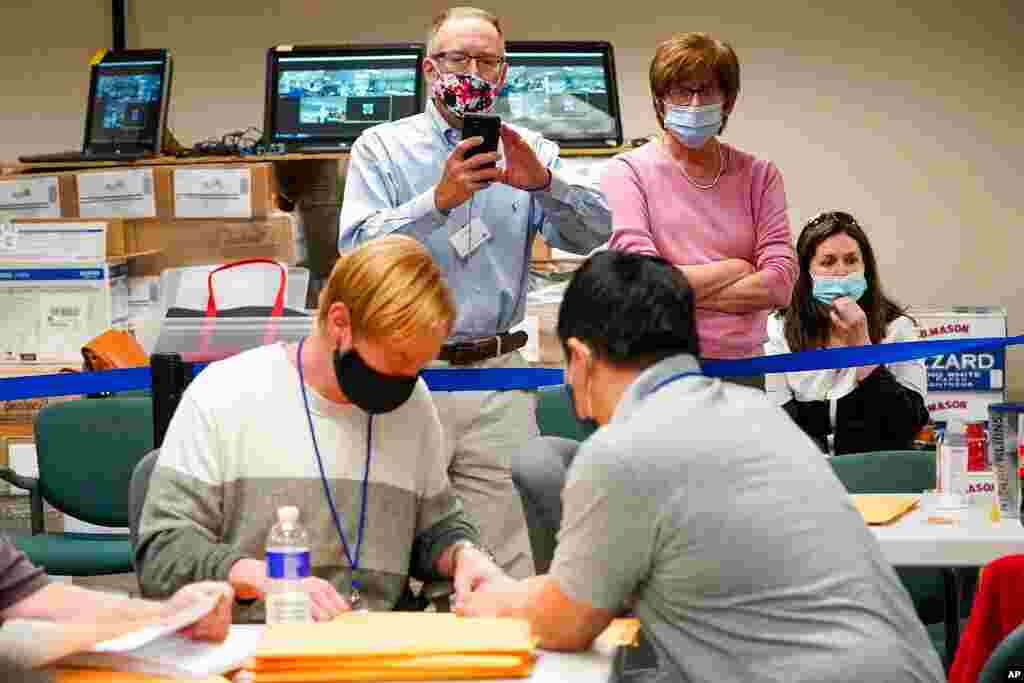 Republican canvas observer Ed White, center, and Democratic canvas observer Janne Kelhart watch as Lehigh County workers count ballots as vote counting in the general election continues, in Allentown, Pennsylvania. 