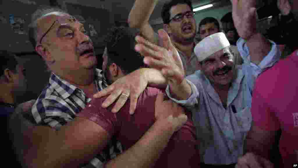 Palestinians mourn their relative in the morgue of the Shifa hospital in Gaza City on July 12, 2014.