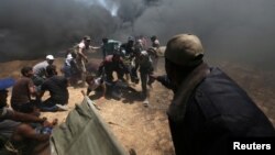 Warga Palestina mengevakuasi para demonstran yang terluka dalam aksi protes di Jalur Gaza, Senin (14/5). 