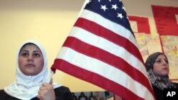 Seorang perempuan Muslim memegang bendera AS dalam sebuah acara di Islamic Center di Dearborn, Michigan. (Foto: Dok)