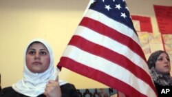 Seorang siswa perempuan Muslim Amerika memegang bendera AS selama berlangsungnya kontes siswa 'Children of the World' di Islamic Center of America di Dearborn, Michigan, 26 Maret 2010. (Foto: dok)