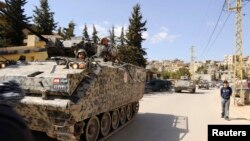 FILE - Lebanese army soldiers patrol the Sunni Muslim border town of Arsal in an armored vehicle.