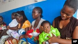 FILE - In this photo taken Nov. 3, 2014, mothers wait inline for their children to be vaccinated by heath workers at the Pipeline Community Health Center, situated on the outskirts of Monrovia, Liberia. 