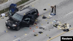 A law enforcement officer looks over the evidence near the remains of a SUV involved in the Wednesdays attack is shown in San Bernardino, California, Dec. 3, 2015. 