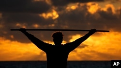 FILE - A beach goer exercises as the sun rises above the Atlantic Ocean, Feb. 1, 2023, in Surfside, Fla. (AP Photo/Wilfredo Lee, File)