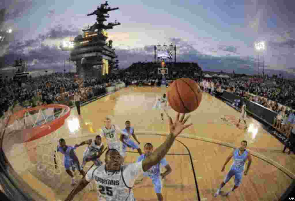 In this image taken with a fisheye lens, Michigan State center Derrick Nix (25) grabs a rebound in front of North Carolina forward John Henson (31), right, during the first half of the Carrier Classic NCAA college basketball game aboard the USS Carl Vinso