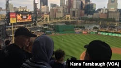 M. Kazam Hashimi and his family, refugees from Afghanistan, attend Hello Neighbor’s Refugee and Immigrant Night at PNC Park, Aug. 1, 2017, with their American mentor Michelle Boehm and her family in Pittsburgh.