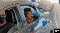 A paramedic with Israel's Magen David Adom (Red Shield of David) national emergency medical service performs a swab test at a drive-thru testing service for COVID-19 coronavirus in Jerusalem, Aug. 27, 2020. 