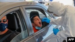 A paramedic with Israel's Magen David Adom (Red Shield of David) national emergency medical service performs a swab test at a drive-thru testing service for COVID-19 coronavirus in Jerusalem, Aug. 27, 2020. 