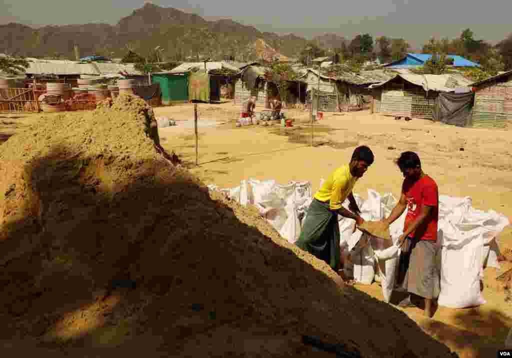 From left, Aman Ullah and Rahamot Ullah full sand bags as part of their work program at the Rohingya refugee camp in Teknaf, Bangladesh on Feb. 12, 2020. Sand bags are used to support tents and build steps around the camps. (Hai Do/VOA)