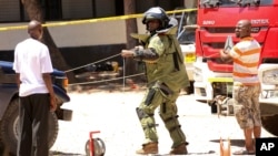 FILE - A member of a bomb disposal team prepares the scene before checking the bodies of three women who were shot dead by police, outside the central police station in the coastal city of Mombasa, Kenya, Sept. 11, 2016. 