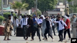 Mahasiswa melemparkan batu ke arah polisi dalam aksi protes atas dugaan pemerkosaan di kampus di Punjab, Rawalpindi, Pakistan, 17 Oktober 2024.