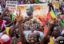 FILE - People hold a banner showing Col. Assimi Goita, leader of the junta running Mali, as they demonstrate to show support for the support for the junta in the capital Bamako, Mali, Sept. 8, 2020.