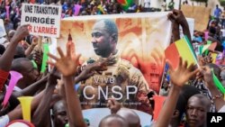 FILE - In this Sept. 8, 2020 photo, people hold a banner showing Col. Assimi Goita, leader of the junta running Mali, as they demonstrate to show support for the junta in Bamako, Mali.
